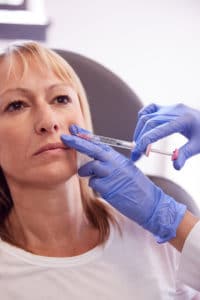 Mature Woman Sitting In Chair Being Give juvederm Injection By Female Doctor